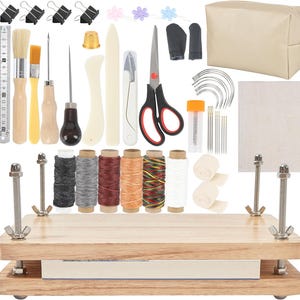 May include: A complete leather crafting kit with various tools, including needles, scissors, brushes, and thread spools. The kit also includes a wooden book press, a beige zippered pouch, and a ruler marked in inches.