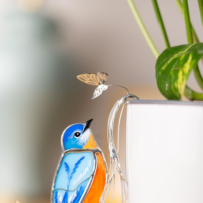 Stunning stained glass bluebird with butterflies and sparkling crystals – a magical touch.