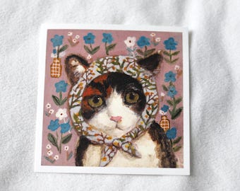 May include: Square print featuring a calico cat wearing a floral headscarf. The cat has green eyes and a pink nose. The background is a muted pink with blue and white floral accents and small vases.