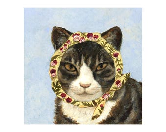 May include: A tabby cat with white markings wears a yellow scarf with a floral pattern. The scarf has red and yellow flowers and green leaves. The cat is looking directly at the viewer.