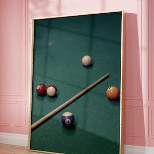 May include: A green felt pool table with a wooden cue stick and five billiard balls. The balls are red, white, and blue, and one ball has the number 12 on it.