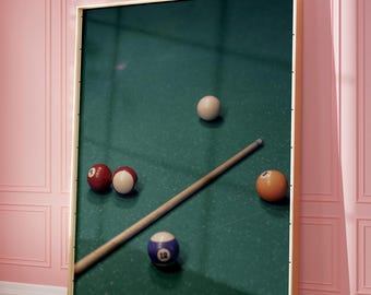 May include: A green felt pool table with a wooden cue stick and five billiard balls. The balls are red, white, and blue, and one ball has the number 12 on it.