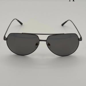 Puede incluir: Gafas de sol aviador negras con doble puente y lentes oscuras. Las gafas de sol tienen un dise&ntilde;o elegante y moderno con montura met&aacute;lica. Las lentes son de color gris oscuro.