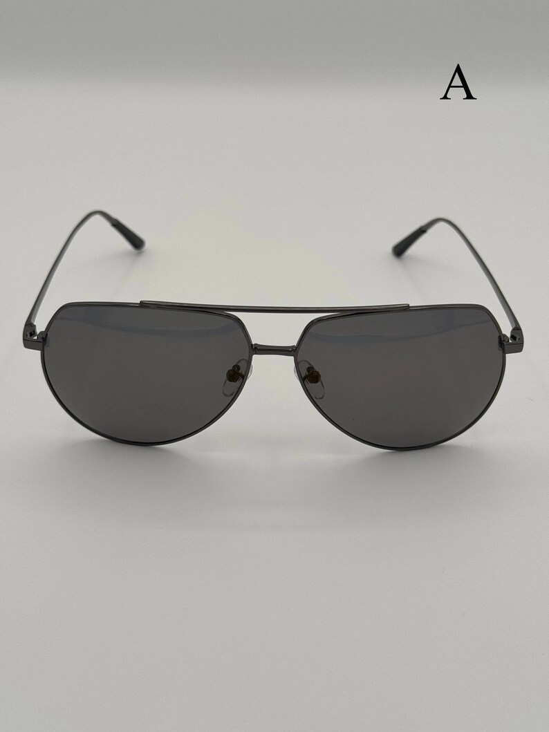 Puede incluir: Gafas de sol aviador negras con doble puente y lentes oscuras. Las gafas de sol tienen un dise&ntilde;o elegante y moderno con montura met&aacute;lica. Las lentes son de color gris oscuro.