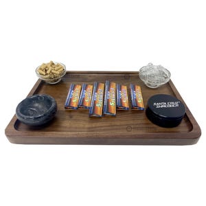 May include: A wooden rolling tray with a black grinder, a glass jar with rolling papers, a small bowl with rolling papers, and six packs of Elements rolling papers.