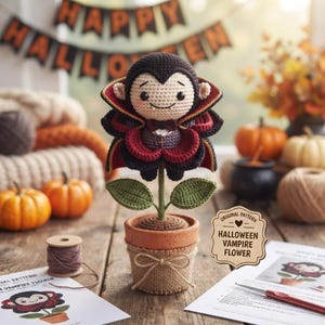 May include: A crocheted vampire flower in a terracotta pot wrapped in burlap with a bow. The vampire has a black cape with red lining, a bow tie, and a small cross. A wooden sign reads ORIGINAL PATTERN HALLOWEEN VAMPIRE FLOWER.