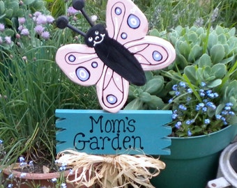 Yard Sign 306 - Mom's Butterfly Garden has a large pink butterfly attached to a sign board with a decorative raffia bow underneath.