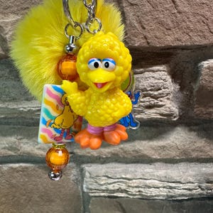 May include: A white ceramic mug with a black handle and the text "But First, Coffee" in a bold, black font. The mug is set against a blurred background, suggesting a cozy setting.