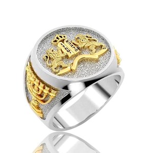 May include: A silver and gold ring with a menorah design on the band and a round top featuring two lions flanking a scroll with Hebrew text.
