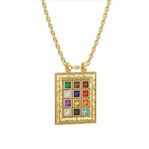Pu&ograve; includere: Una collana d'oro con un ciondolo che presenta una cornice quadrata con 12 pietre preziose colorate. Il ciondolo ha un design elaborato ed &egrave; su una catena delicata.