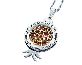 May include: Silver necklace with a pomegranate pendant featuring red gemstones and Hebrew text. The pendant is detailed with a gold-toned interior.