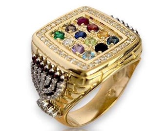 May include: A gold ring with a square-shaped center featuring a colorful gemstone design surrounded by smaller diamonds. The ring band is decorated with a menorah design.