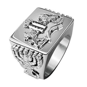 May include: A silver ring with a square top featuring a detailed design of a lion and a menorah. The ring band is also decorated with a menorah design.