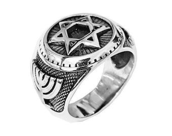 May include: A silver ring with a detailed design featuring a Star of David and a menorah. The ring has a textured finish and a polished band.