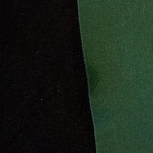 May include: Close-up of two fabric swatches. One is solid black, the other is a dark green. Both fabrics have a soft, velvety texture. The image highlights the contrast between the two colours and textures.