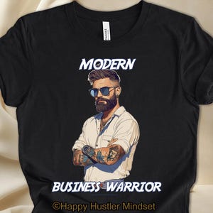 May include: Black t-shirt featuring a graphic of a bearded man with tattoos. The text "MODERN BUSINESS WARRIOR" is printed on the shirt. The text "Happy Hustler Mindset" is printed below the graphic.
