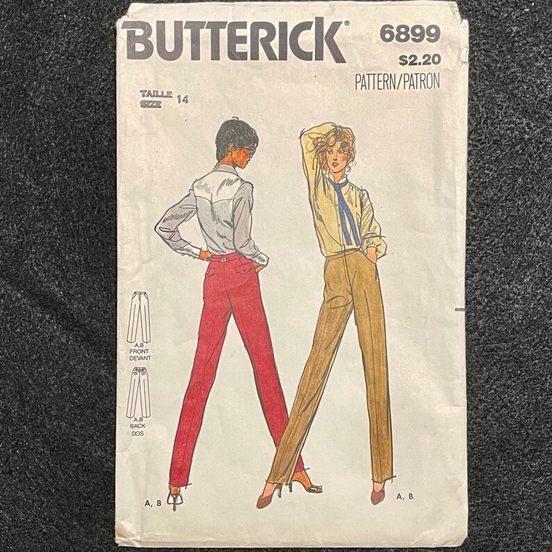 May include: A vintage sewing pattern for trousers, size 14, from Butterick pattern number 6899. The pattern is for a pair of trousers with a wide leg and a high waist. The pattern is illustrated with two figures wearing the trousers, one in red and one in brown.