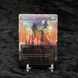 Puede incluir: Una carta coleccionable rectangular titulada Demonic Tutor con un acabado holográfico y la ilustración de un personaje de pelo largo y oscuro. El texto de la carta dice Sorcery, Search your library for a card, put that card into your hand, then shuffle.