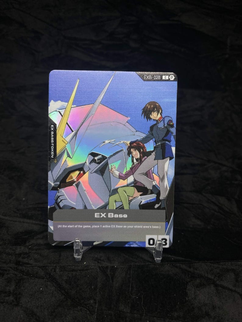 May include: A holographic trading card featuring anime characters and a mecha. The card has the text "EX Base" and "EXB-028". The card is displayed on a clear plastic stand.