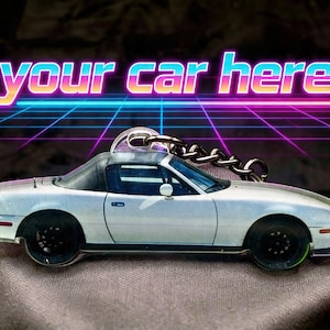 Peut inclure: Un porte-clés représentant une voiture décapotable blanche avec des roues noires et un toit noir. Le porte-clés est orné d'une chaîne argentée et d'une boucle métallique. Le texte "your car here" est affiché en police rétro.