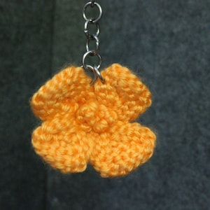 A crocheted keychain of a California poppy.