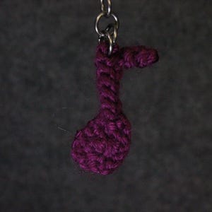 Könnte beinhalten: Ein lila gehäkelter Musiknotenschlüsselanhänger.