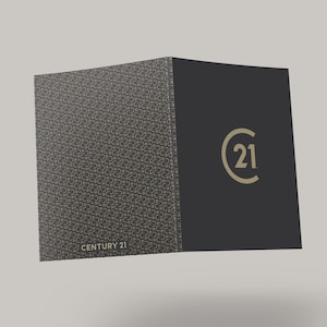 May include: A dark gray presentation folder with a gold pattern and the words "CENTURY 21" printed on the front. The right side of the folder is solid dark gray with the "21" logo in gold.