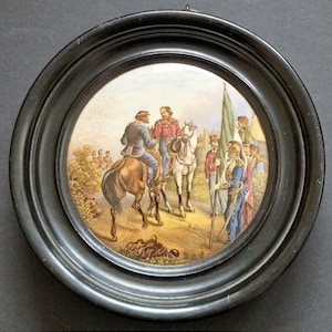 Pode incluir: Uma placa de parede circular com uma ilustração histórica detalhada de soldados a cavalo e a pé numa paisagem, inserida numa moldura preta, lisa e arredondada. A cena mostra figuras com uniformes militares.