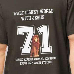 May include: Dark olive green t-shirt with the text "WALT DISNEY WORLD WITH JESUS" above a large white "71" and a lion graphic. Below the number are the words "MAGIC KINGDOM ANIMAL KINGDOM EPCOT HOLLYWOOD STUDIOS".