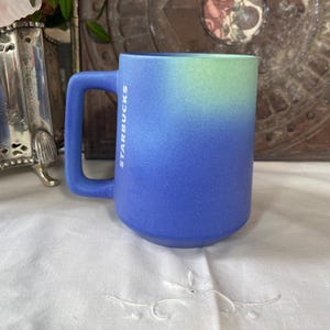 Tazas de café de cerámica Starbucks con diseño artesanal en tonos marrón, blanco y azul degradado.