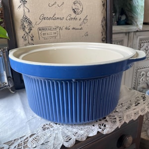 Pode incluir: Uma travessa de cerâmica azul e branca com exterior canelado. O prato tem uma borda larga e plana e duas pequenas alças. O interior é branco e o exterior é azul vibrante.