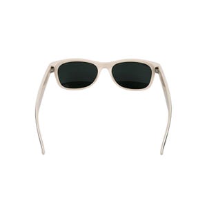 Puede incluir: Gafas de sol blanquecinas con lentes oscuras. Las gafas tienen una montura rectangular cl&aacute;sica y patillas rectas. Las lentes son oscuras, proporcionando sombra y protecci&oacute;n solar. Sobre un fondo blanco.