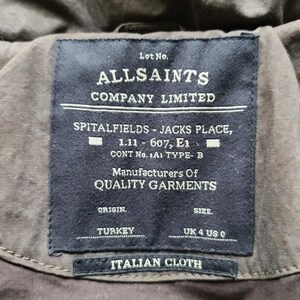 May include: Close-up of a dark navy label from AllSaints Company Limited. The label includes text such as "Spitalfields - Jacks Place" and "Italian Cloth". The label also indicates the origin is Turkey and the size is UK 4 US 0.