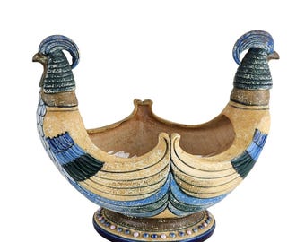 Könnte beinhalten: Dekorativer Keramik-Blumentopf in Bootsform mit vogelartigen Figuren an beiden Enden. Der Topf ist in Blau-, Beige- und Brauntönen bemalt, mit aufwendigen Details und einem runden Sockel. Das Design ist kunstvoll und künstlerisch, etwa 30 cm lang.