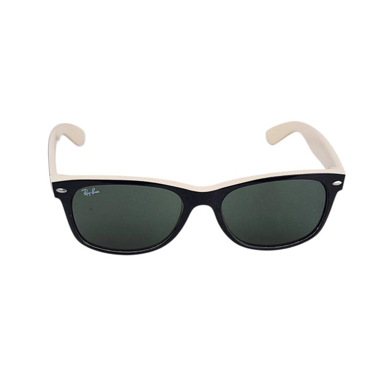 Puede incluir: Gafas de sol negras con montura blanca y lentes verdes. Las gafas de sol tienen una forma rectangular cl&aacute;sica. El logotipo de Ray-Ban es visible en la lente.