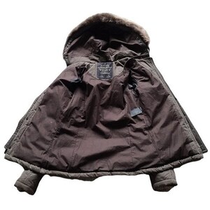May include: A brown winter coat with a faux fur-lined hood. The coat is open, revealing a dark brown interior lining and a label near the collar. The coat has a quilted design and two pockets.