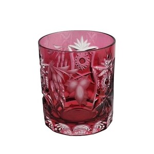 May include: A ruby-colored, cut-glass tumbler with intricate floral and geometric designs. The glass features etched grape clusters, starbursts, and leaf patterns. The tumbler is a classic shape, perfect for serving beverages.