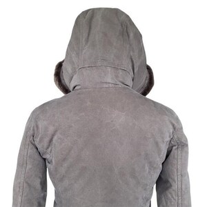 May include: A gray hooded jacket with a fur-lined hood. The jacket is viewed from the back, showcasing the hood and the upper back of the garment. The jacket appears to be made of a durable, possibly waxed, material.