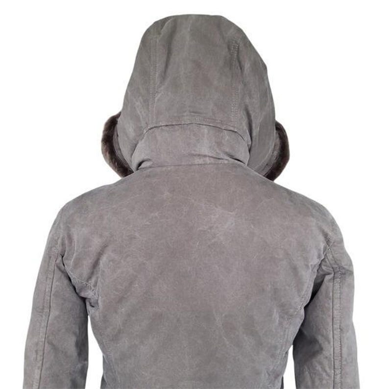 May include: A gray hooded jacket with a fur-lined hood. The jacket is viewed from the back, showcasing the hood and the upper back of the garment. The jacket appears to be made of a durable, possibly waxed, material.