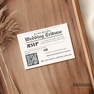 May include: A wedding RSVP card designed to look like a newspaper clipping from The New York City Wedding Tribune. The card includes a QR code, RSVP details, and a website address. The card is on a wooden surface.