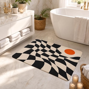 May include: A rectangular bath mat featuring a black and off-white wavy checkerboard pattern with a solid orange circle positioned in the upper right corner. The mat has rounded corners and is placed on a light-colored marble bathroom floor.