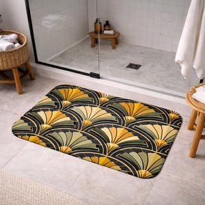 May include: A rectangular bath mat featuring a fan-shaped design in yellow, green, and gold hues set against a black backdrop. The mat is positioned in a bathroom, near a shower and a small wooden stool.