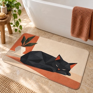 Può includere: Un tappetino da bagno rettangolare con un gatto nero geometrico sdraiato su uno sfondo beige e terracotta. Il design include una pianta in vaso stilizzata in un contenitore bianco geometrico, con linee angolari che definiscono la forma.