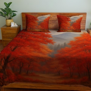 May include: A bedding set featuring a vibrant autumn forest scene. The duvet cover and two pillowcases display a landscape of red and orange trees, with a path leading into the distance. The design evokes a sense of warmth and natural beauty.