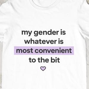 Può includere: Una t-shirt bianca a maniche corte con il testo nero 'my gender is whatever is most convenient to the bit', con le parole 'most convenient' evidenziate da uno sfondo rettangolare viola chiaro e una piccola icona a forma di cuore viola sotto.