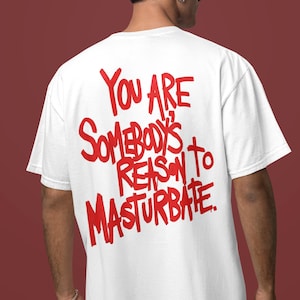 May include: White t-shirt with the red text "YOU ARE SOMEBODY'S REASON TO MASTURBATE" on the back. The shirt is a crew neck style and appears to be made of cotton. The background is a solid maroon color.