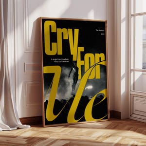 May include: A framed poster with a black background and yellow text that reads "Cry For Me." The poster features an image of a performer on stage. Text at the top reads "The Weeknd 2025." Below the main text is "A single from the album Hurry Up Tomorrow."