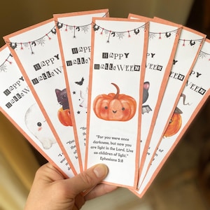 May include: A selection of Halloween bookmarks with orange borders. Each bookmark displays "Happy Halloween" and a spooky illustration, such as a ghost, cat, and pumpkin. Some bookmarks also feature Bible verses.