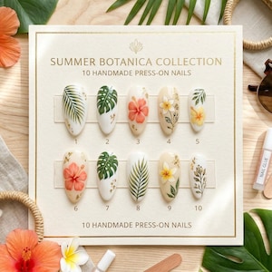 May include: A display of ten handmade press-on nails from the Summer Botanica Collection, each with a unique floral or leaf design. The nails are arranged on a cream-colored card, with nail glue and a wooden file visible.