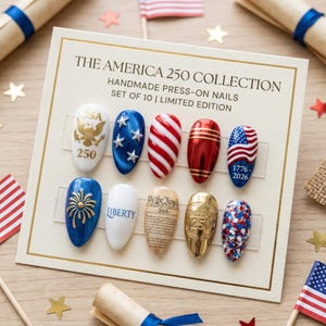 May include: A set of ten handmade press-on nails with patriotic designs. The nails feature the text "USA 250", stars, red and white stripes, the American flag, and the text "LIBERTY" and "FREEDOM 250". The set is part of "THE AMERICA 250 COLLECTION".